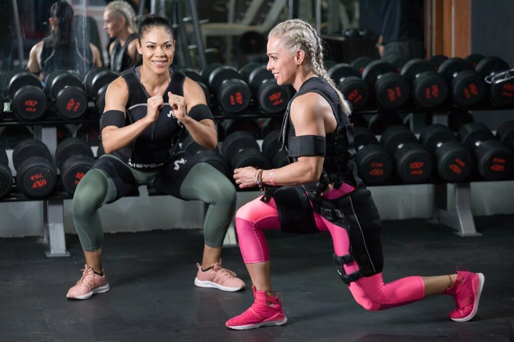 Two women engaged in strength training at a gym, showing determination.